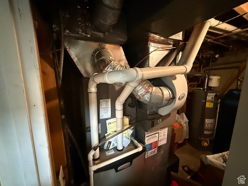 Utility room featuring strapped water heater