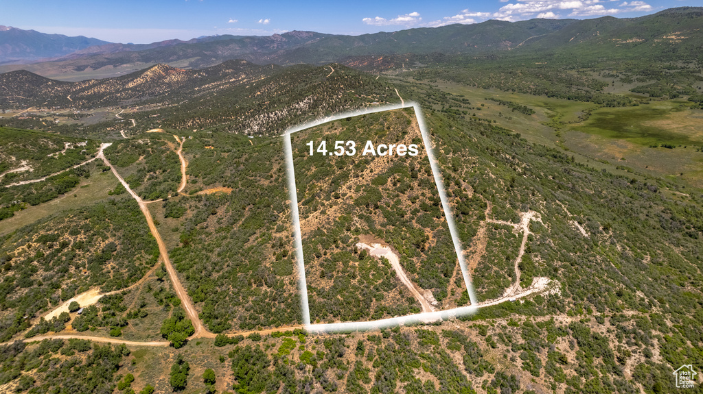 Aerial view of property and surrounding area with a mountainous background and property boundaries highlighted