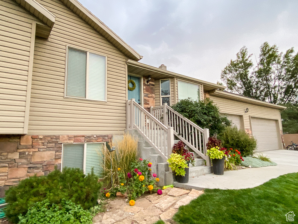 View of front of home featuring driveway, stone siding, and a garage
