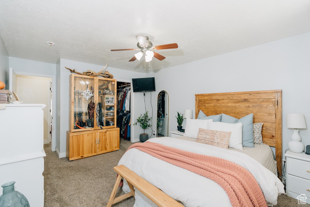 Carpeted bedroom featuring a closet, a spacious closet, and ceiling fan