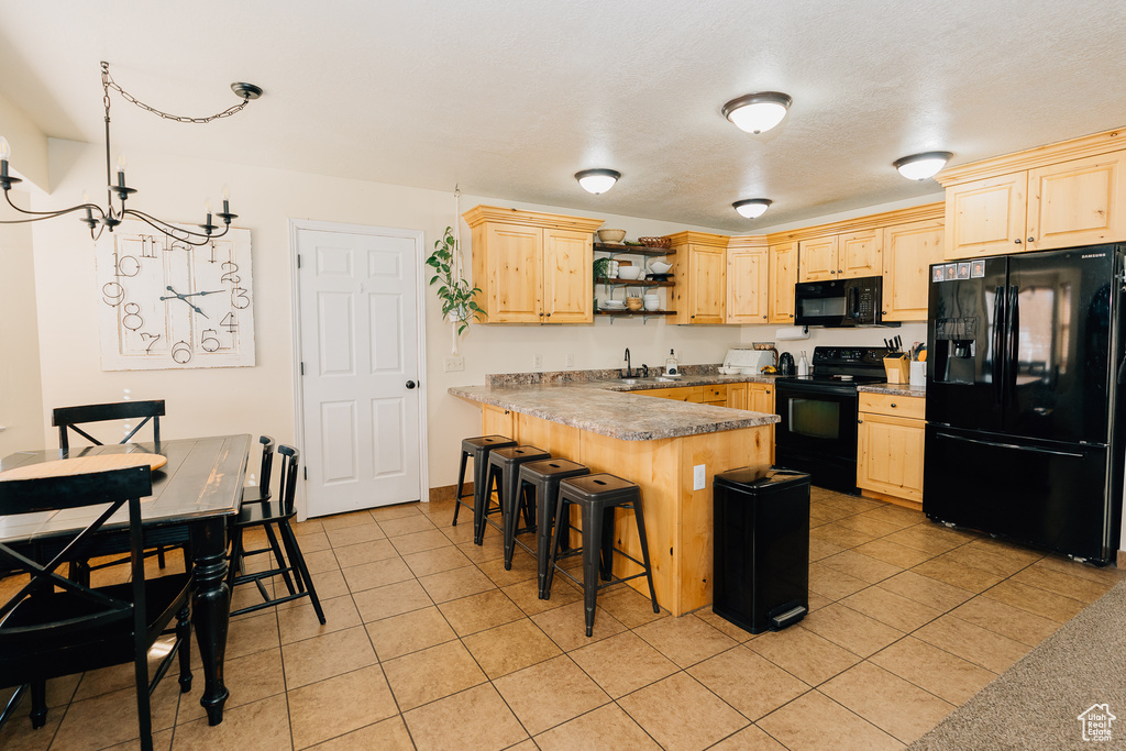 Kitchen with black appliances, light brown cabinets, open shelves, a peninsula, and light tile patterned floors