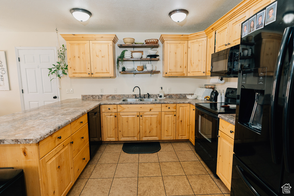 Kitchen featuring black appliances, a peninsula, and light brown cabinets