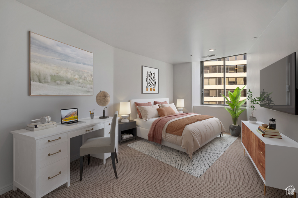 Bedroom with light colored carpet and an office area