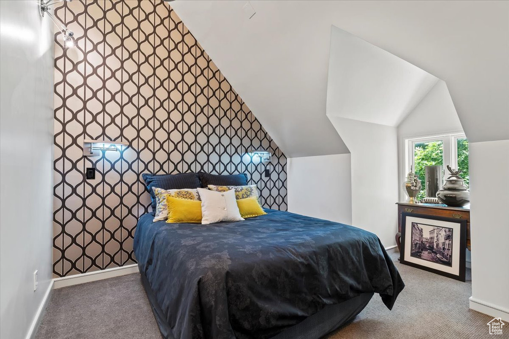 Carpeted bedroom with lofted ceiling and an accent wall