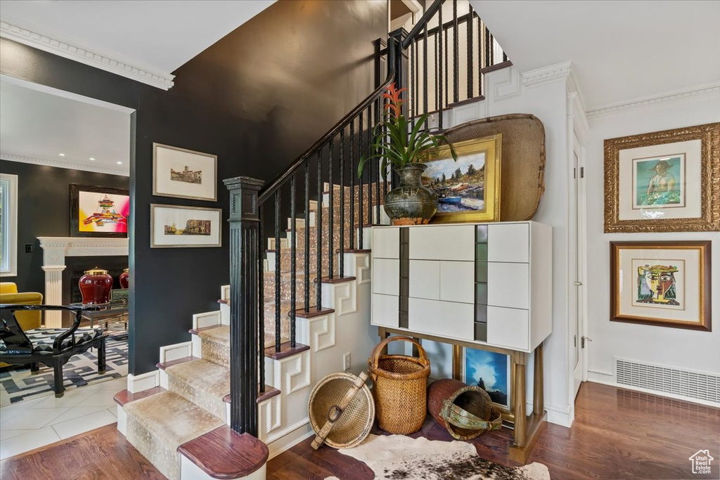 Stairs featuring ornamental molding and wood finished floors