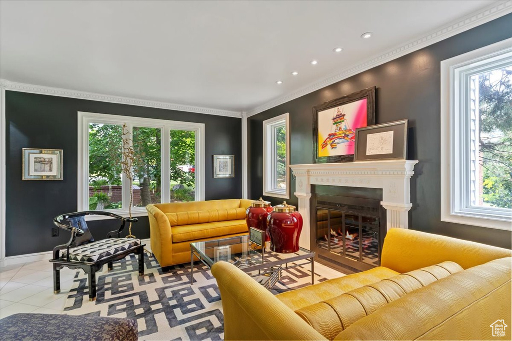 Tiled living room featuring plenty of natural light, ornamental molding, a glass covered fireplace, and recessed lighting