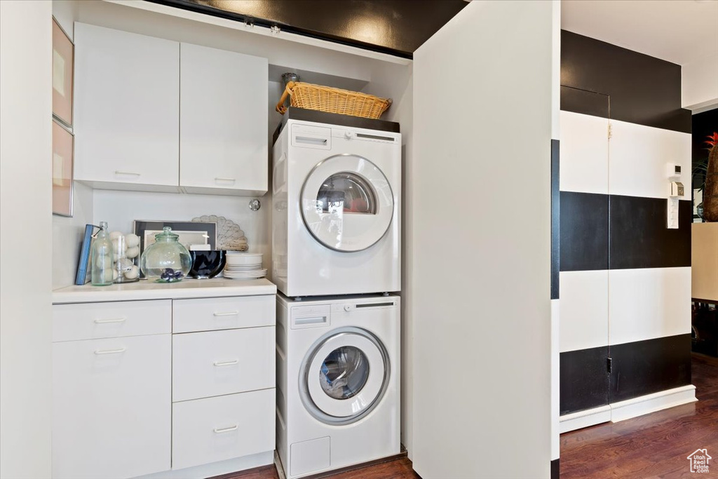 Washroom featuring stacked washer / drying machine and dark wood-type flooring