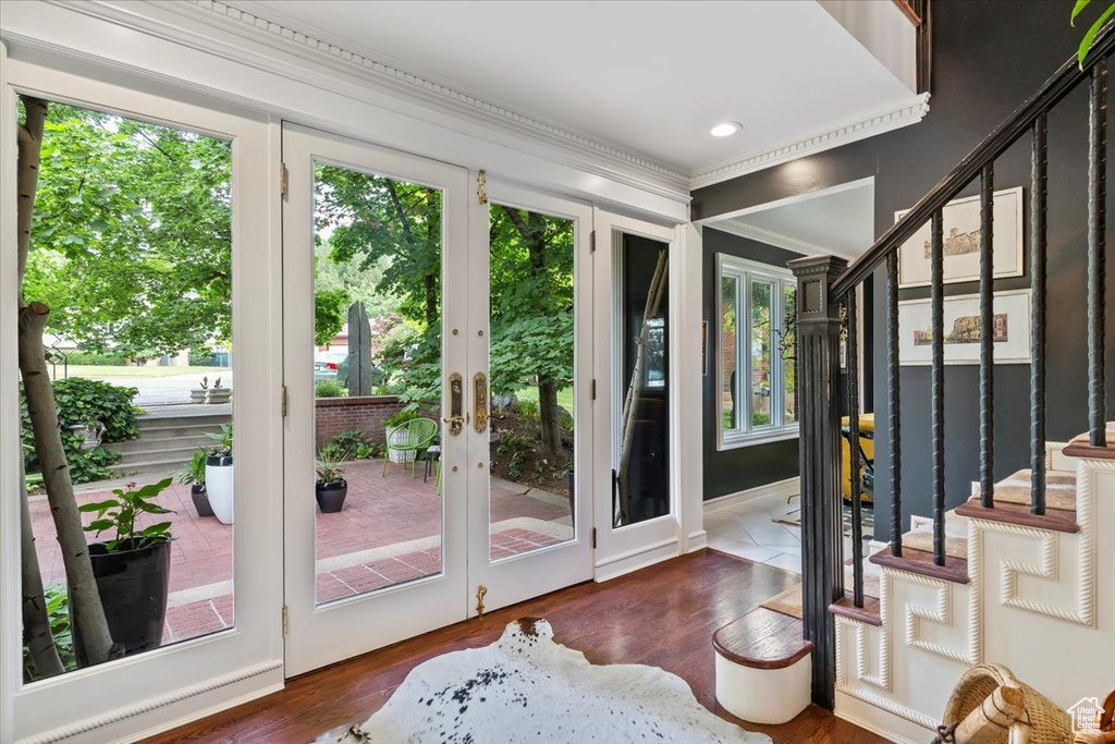 Doorway to outside featuring wood finished floors, french doors, ornamental molding, and stairway