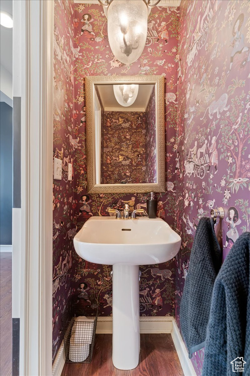 Bathroom featuring wood finished floors and wallpapered walls