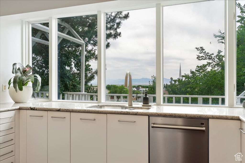 Kitchen featuring dishwasher, white cabinets, light stone countertops, and a mountain view