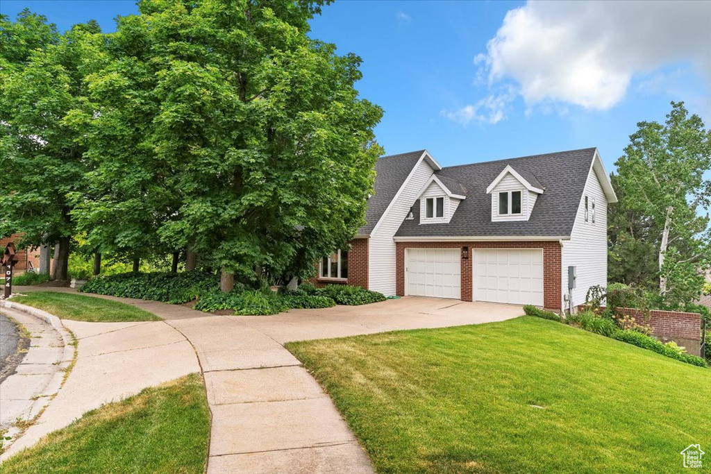 View of front of home featuring brick siding, concrete driveway, a front yard, a shingled roof, and an attached garage