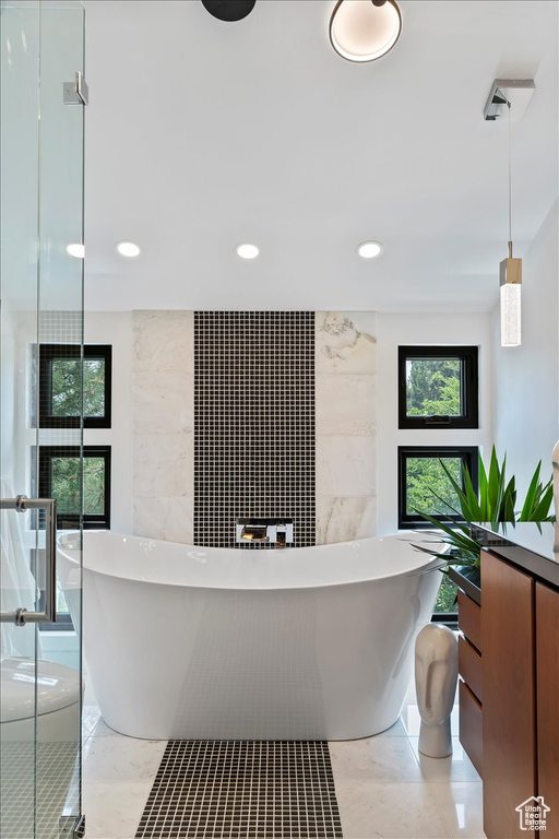 Bathroom featuring a freestanding tub, recessed lighting, vanity, a shower, and tile walls