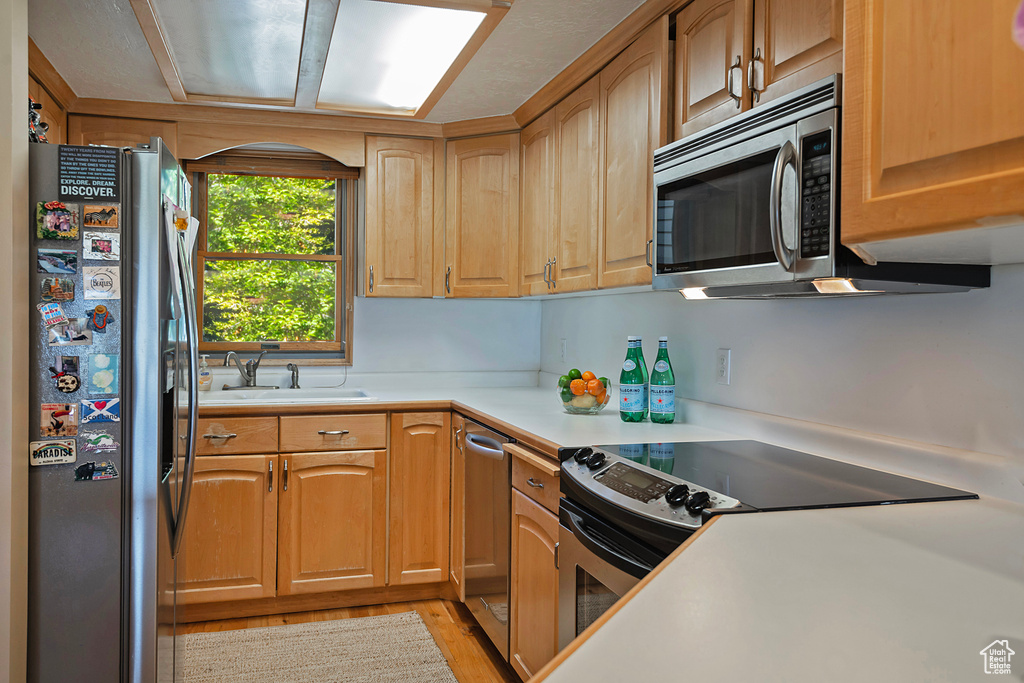 Kitchen featuring stainless steel appliances, light countertops, and light wood-style flooring