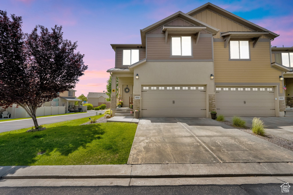 View of front of home with stone siding, a front lawn, an attached garage, and driveway