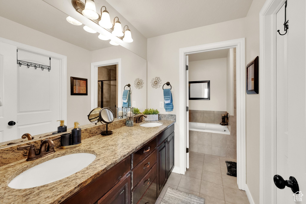 Bathroom featuring tile patterned flooring, double vanity, a garden tub, and a tile shower