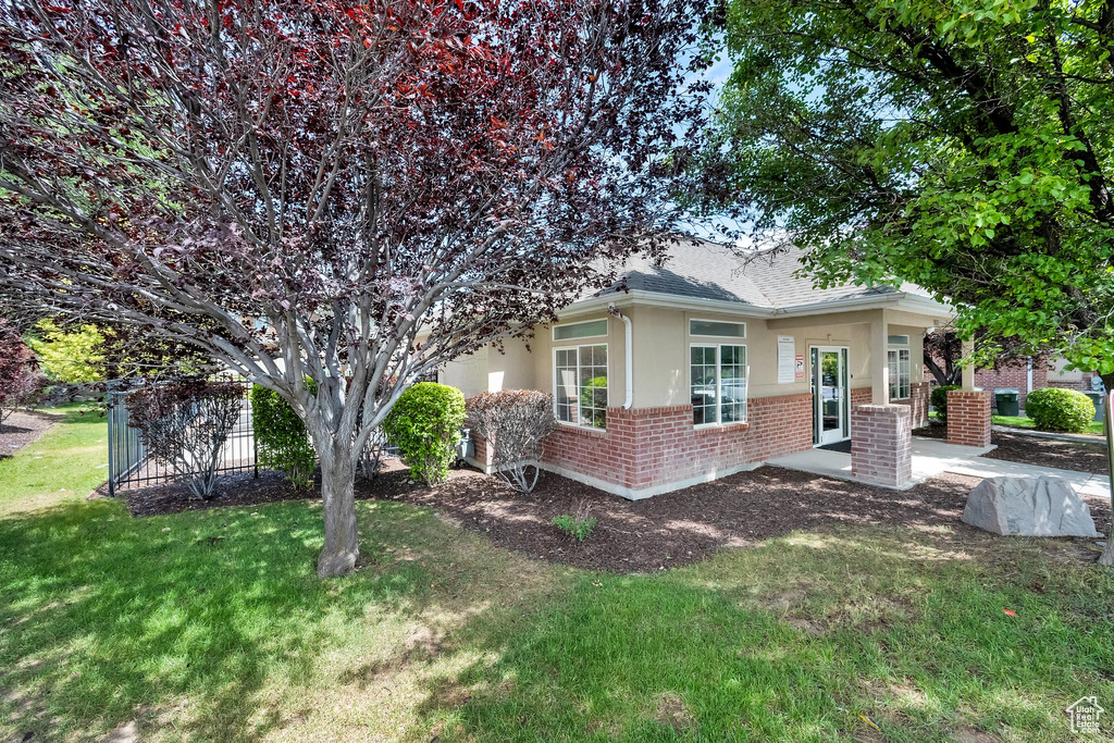 View of front of home featuring stucco siding, brick siding, a front lawn, and roof with shingles