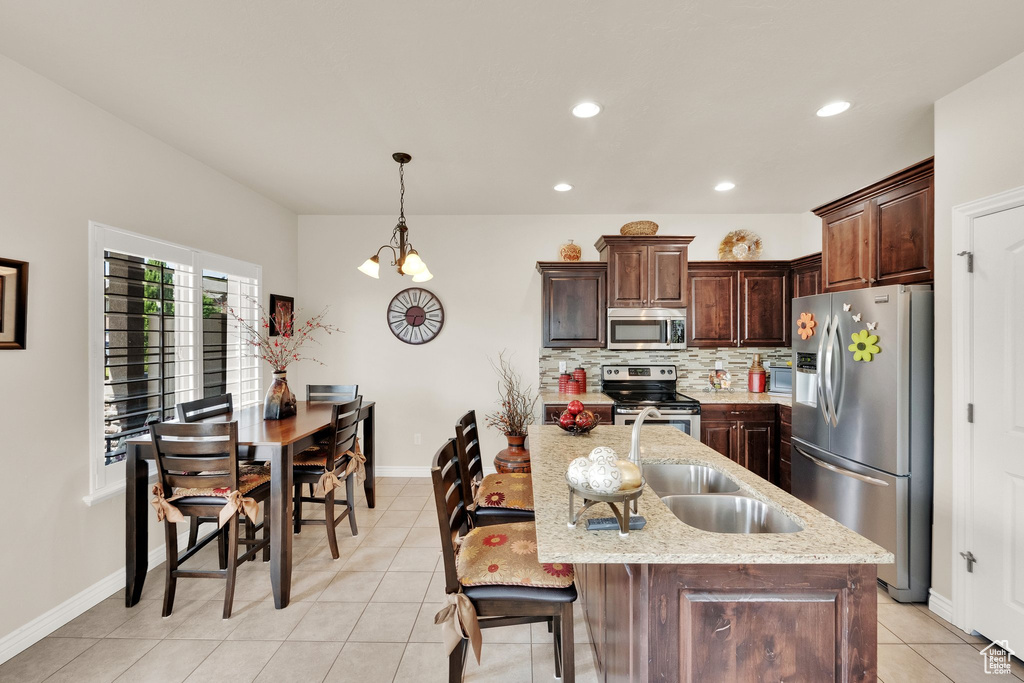 Kitchen with stainless steel appliances, light tile patterned flooring, recessed lighting, backsplash, and dark brown cabinetry
