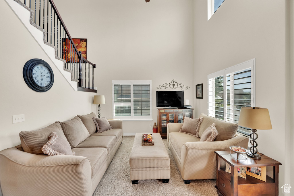 Carpeted living room with a high ceiling and stairway