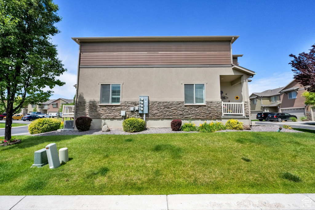 View of property exterior with stucco siding, stone siding, and a lawn