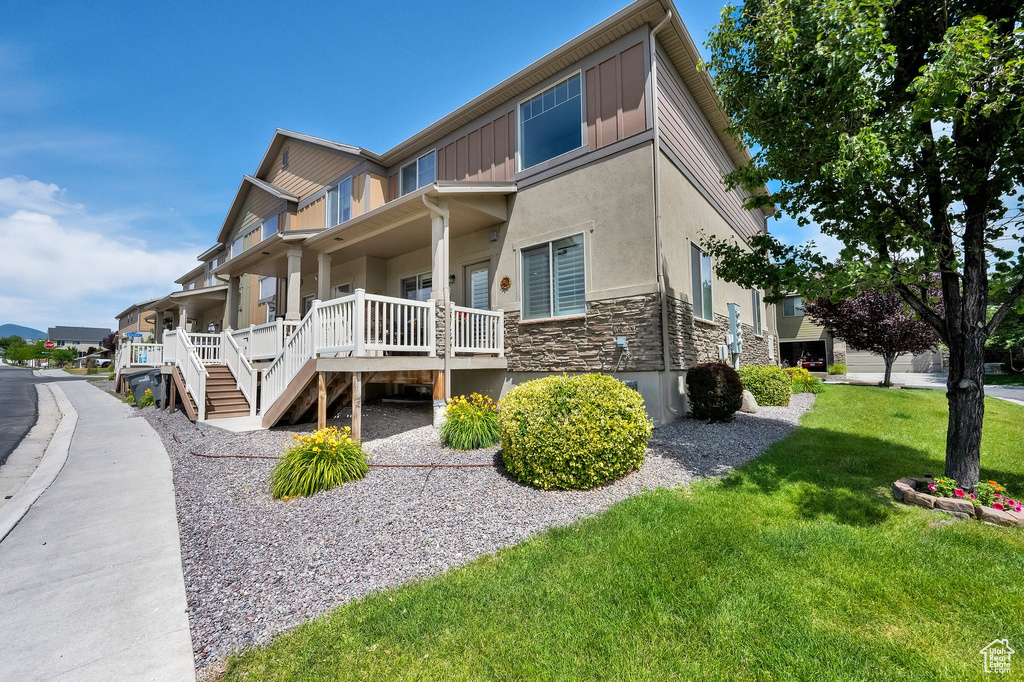 View of home\\\\\\\'s exterior with stone siding, a porch, stucco siding, a lawn, and stairway