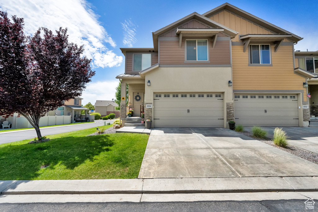 View of front of property with stone siding, an attached garage, and a front lawn