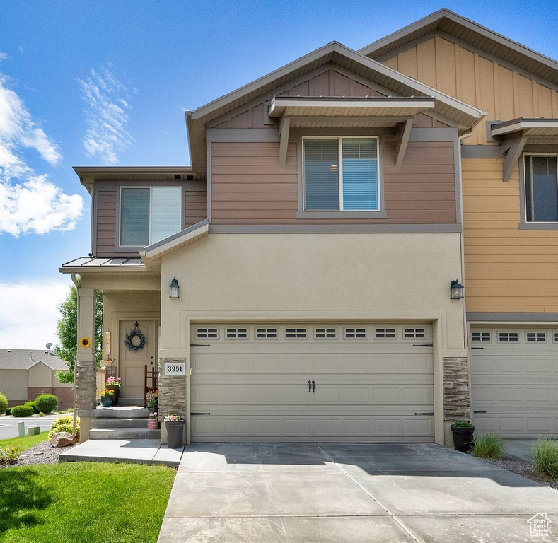 View of front of home featuring stone siding, a garage, driveway, board and batten siding, and stucco siding