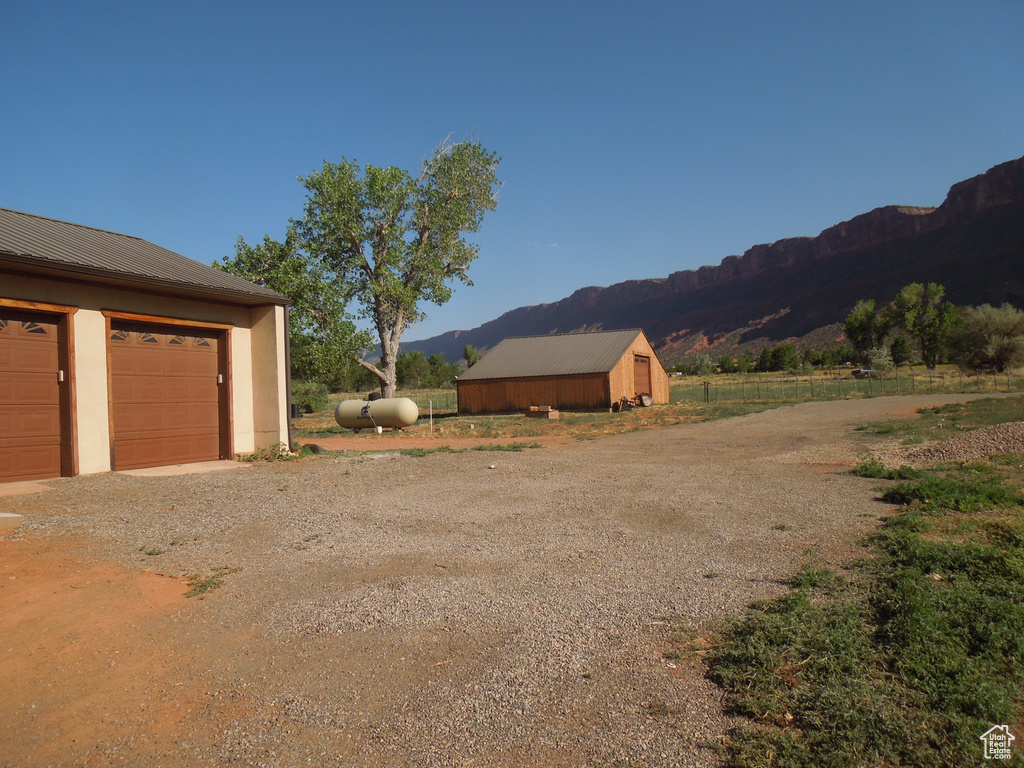 View of yard with a mountain view, driveway, an outdoor structure, and a garage