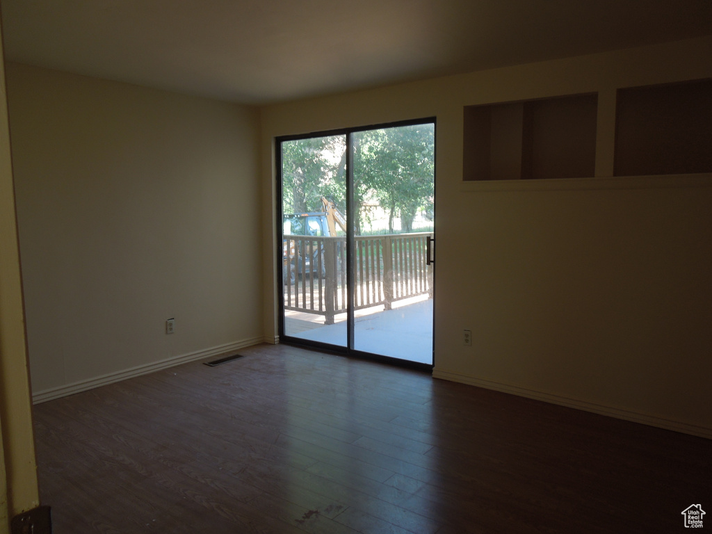 Unfurnished room with dark wood-type flooring and baseboards