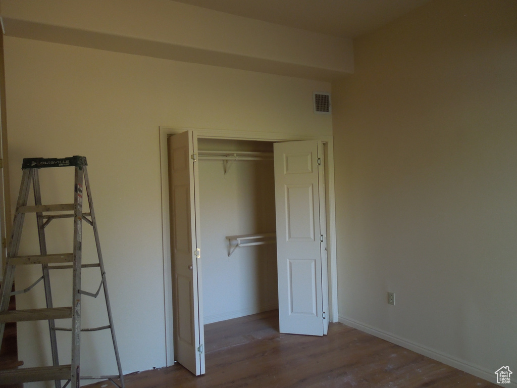 Unfurnished bedroom with wood finished floors and a closet
