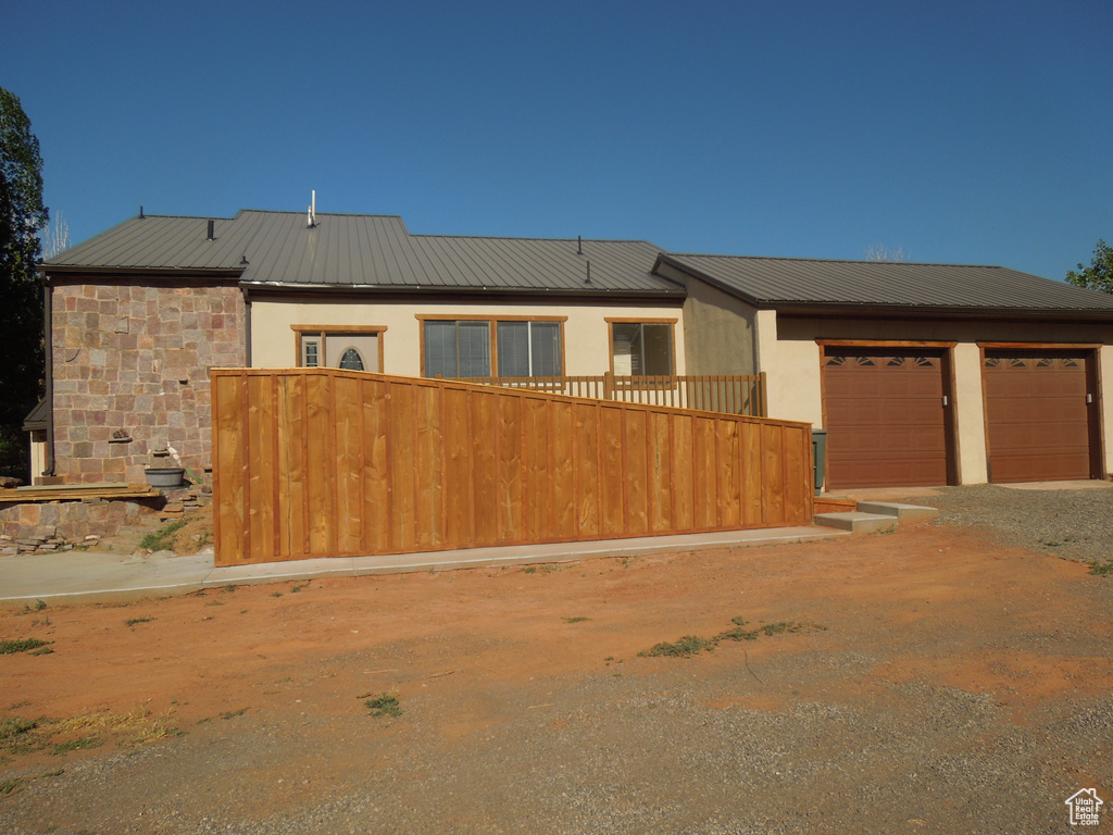 View of front facade featuring a metal roof, driveway, a garage, and stucco siding