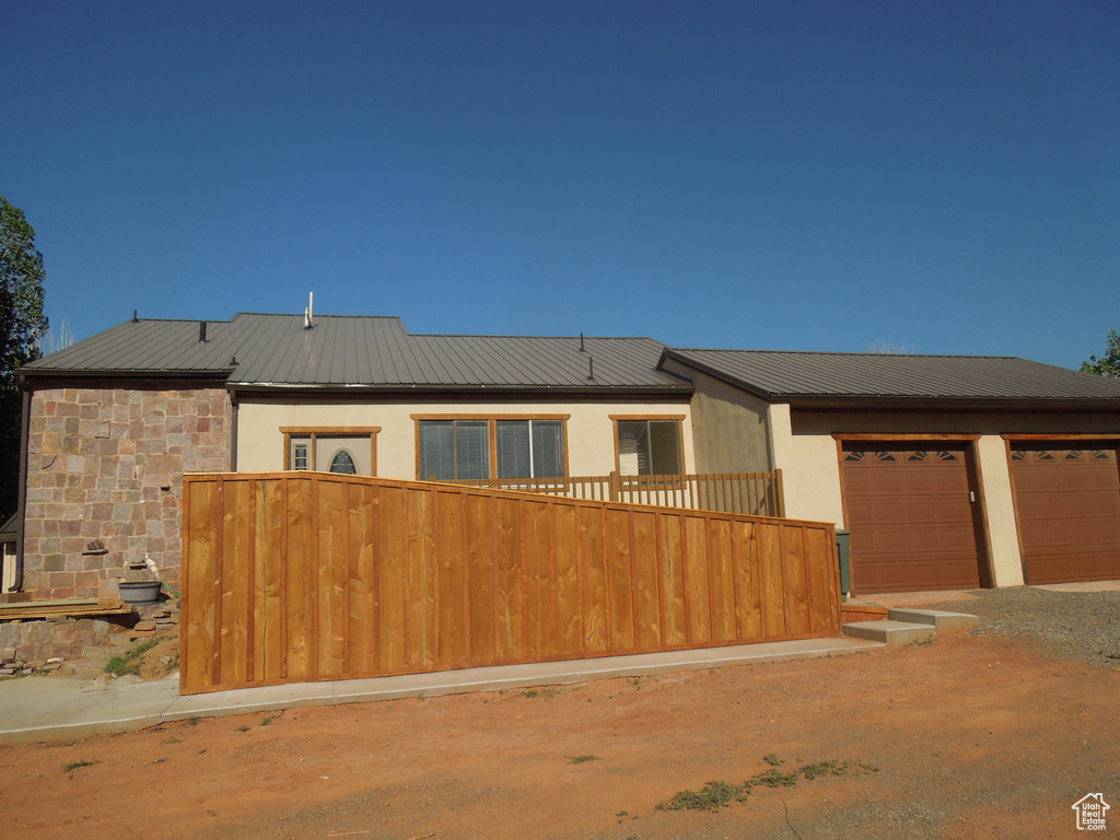 View of front of property with a metal roof, driveway, stucco siding, and an attached garage