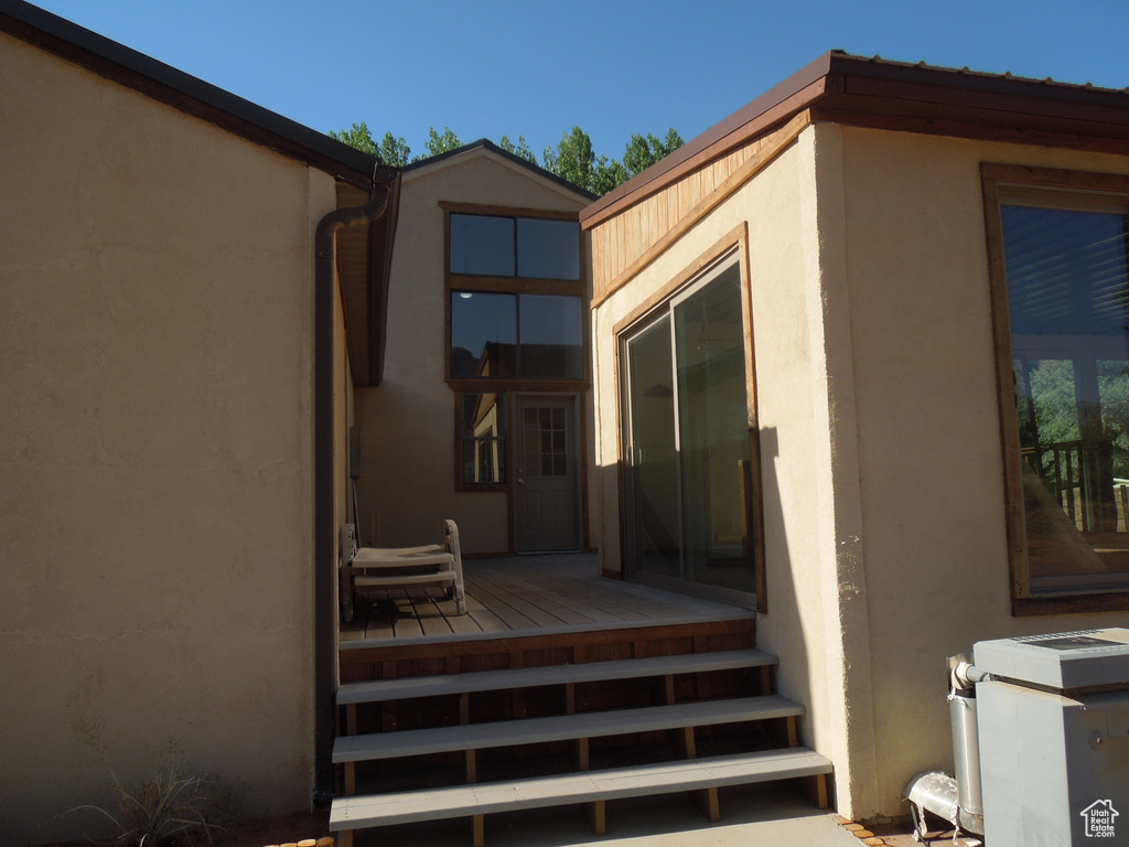 View of exterior entry featuring stucco siding and a wooden deck