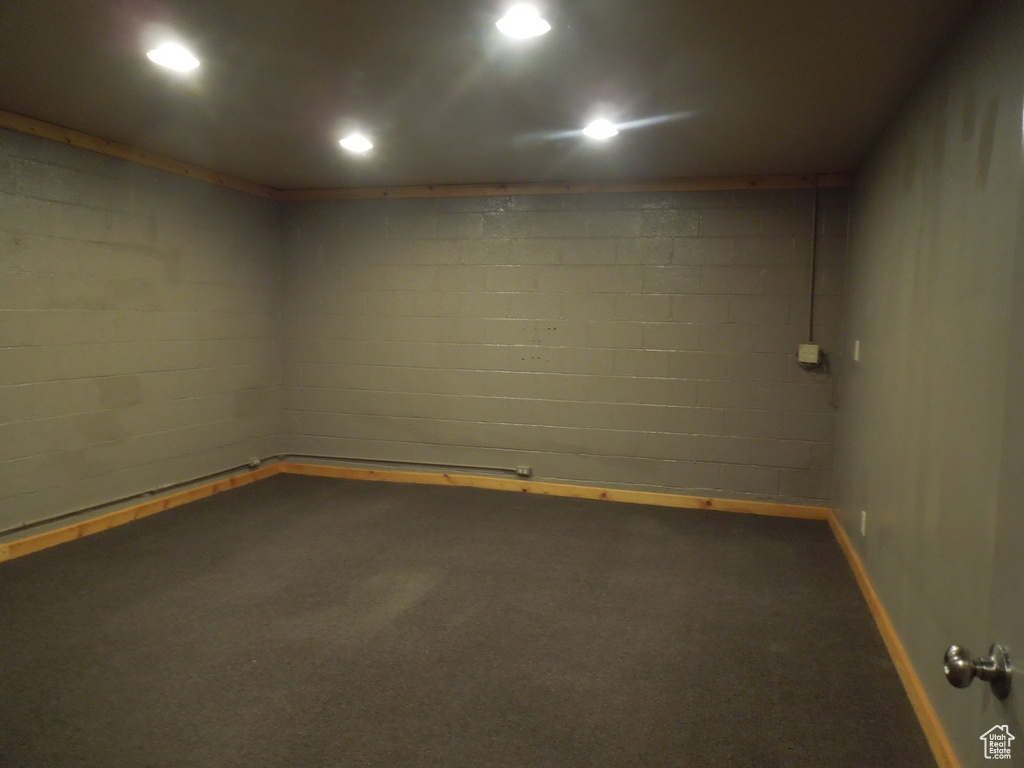 Empty room featuring carpet floors and concrete block wall