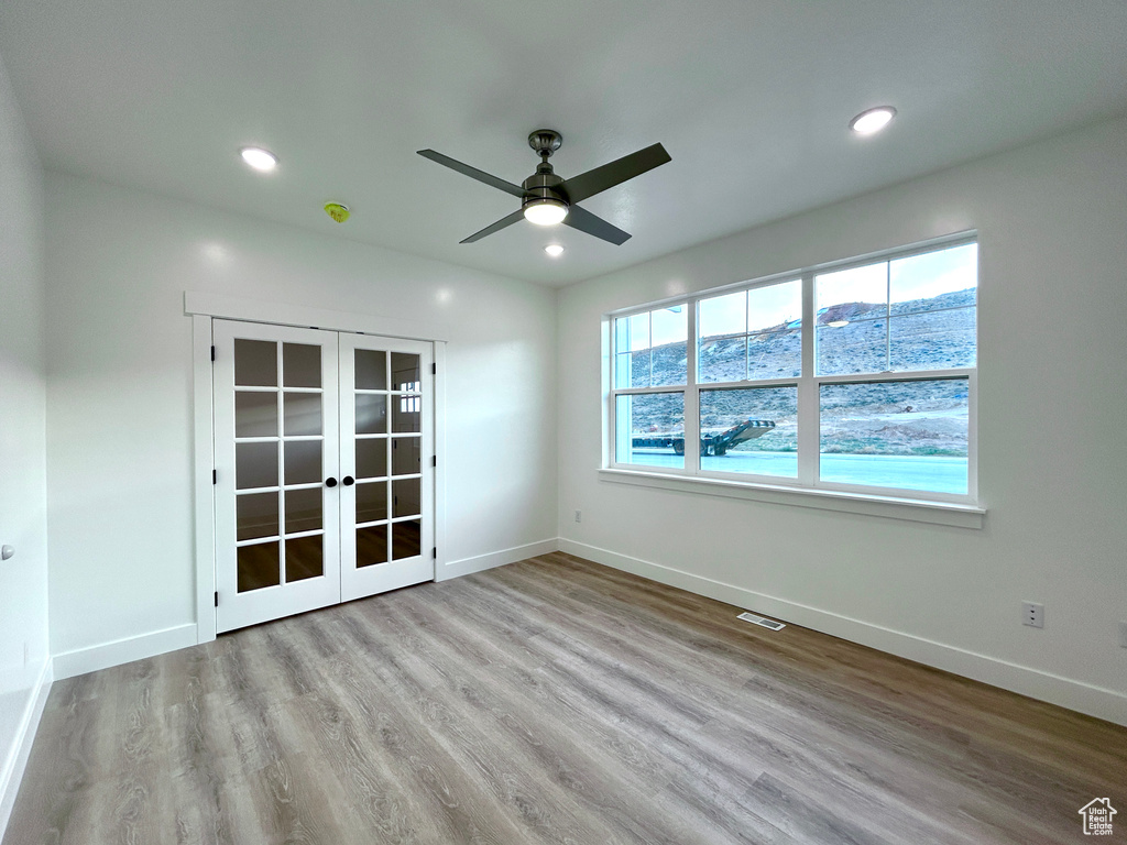 Empty room featuring french doors, wood finished floors, ceiling fan, and recessed lighting