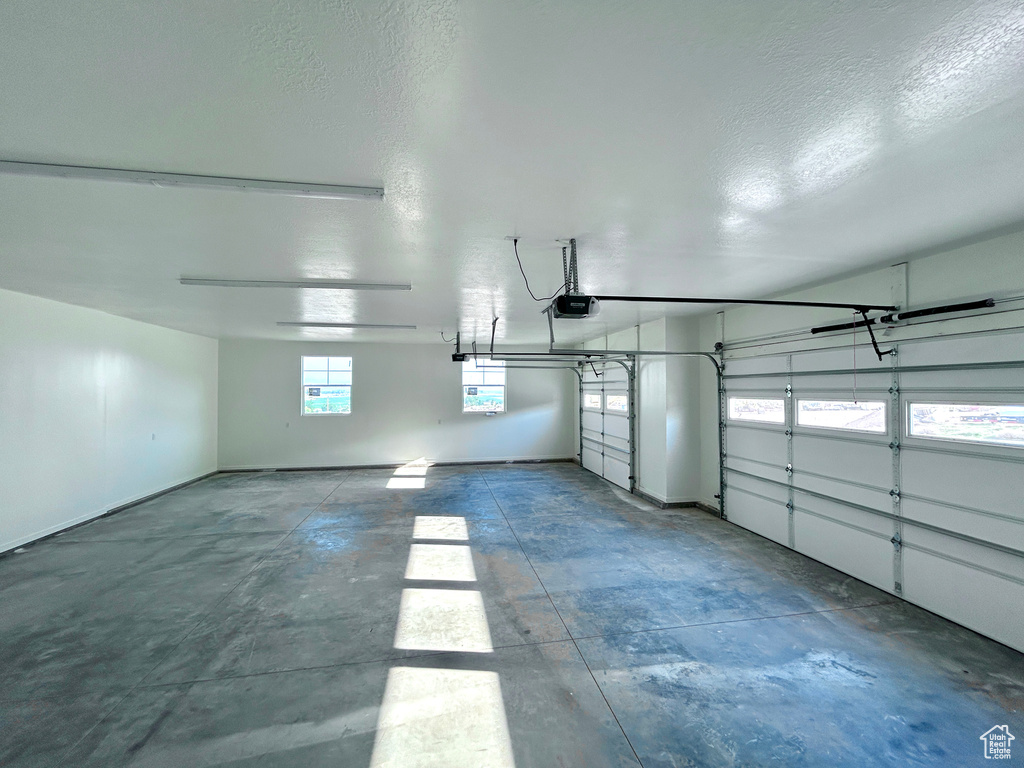 Garage featuring a garage door opener and baseboards
