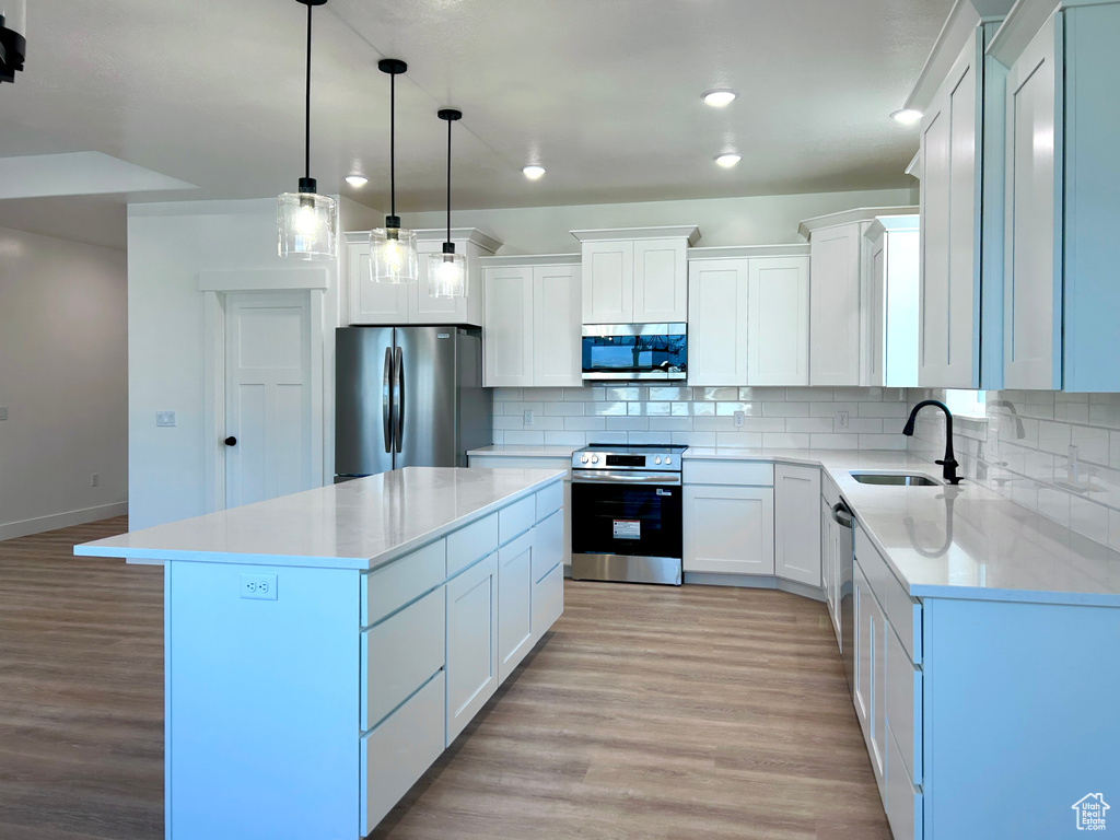 Kitchen featuring appliances with stainless steel finishes, light wood-style floors, decorative backsplash, a kitchen island, and recessed lighting