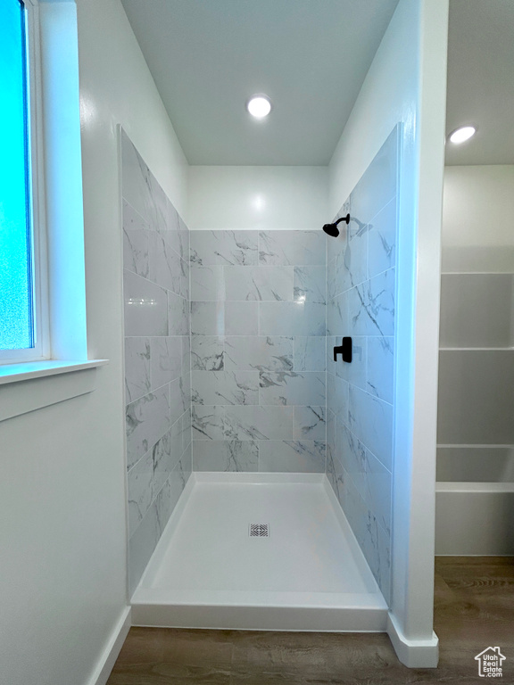 Bathroom with tiled shower, wood finished floors, and recessed lighting