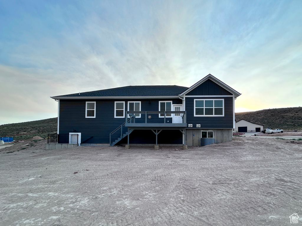 Back of house at dusk featuring a wooden deck and stairs