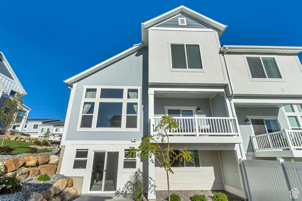Rear view of property with stucco siding and a balcony