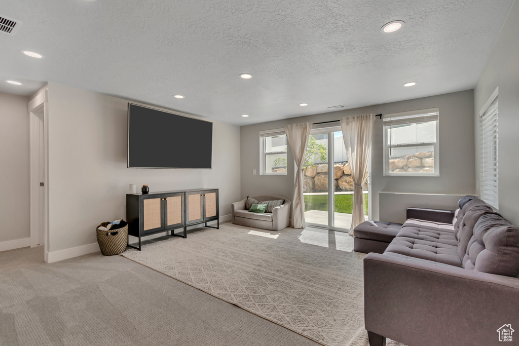 Living area with light colored carpet, recessed lighting, and a textured ceiling