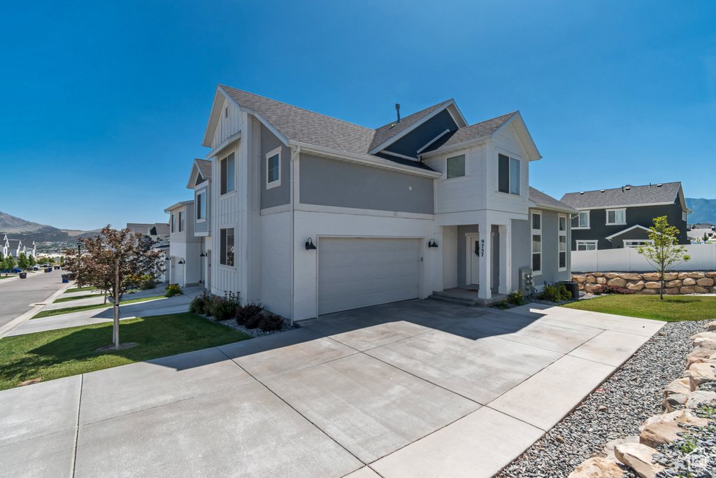 View of front of home with roof with shingles, driveway, stucco siding, a garage, and a mountain view