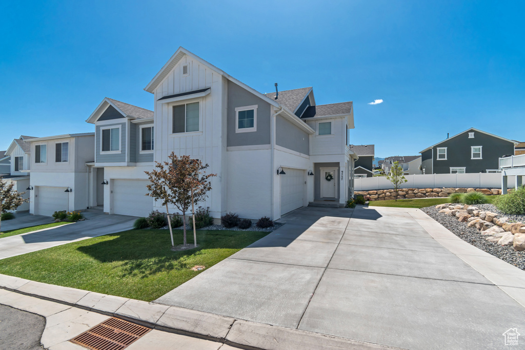 View of front of house featuring an attached garage, concrete driveway, a residential view, and board and batten siding