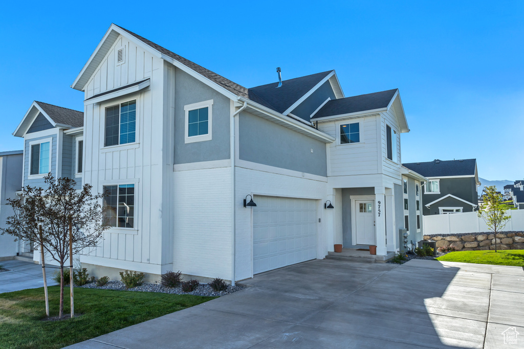 View of front of house with board and batten siding, driveway, and an attached garage