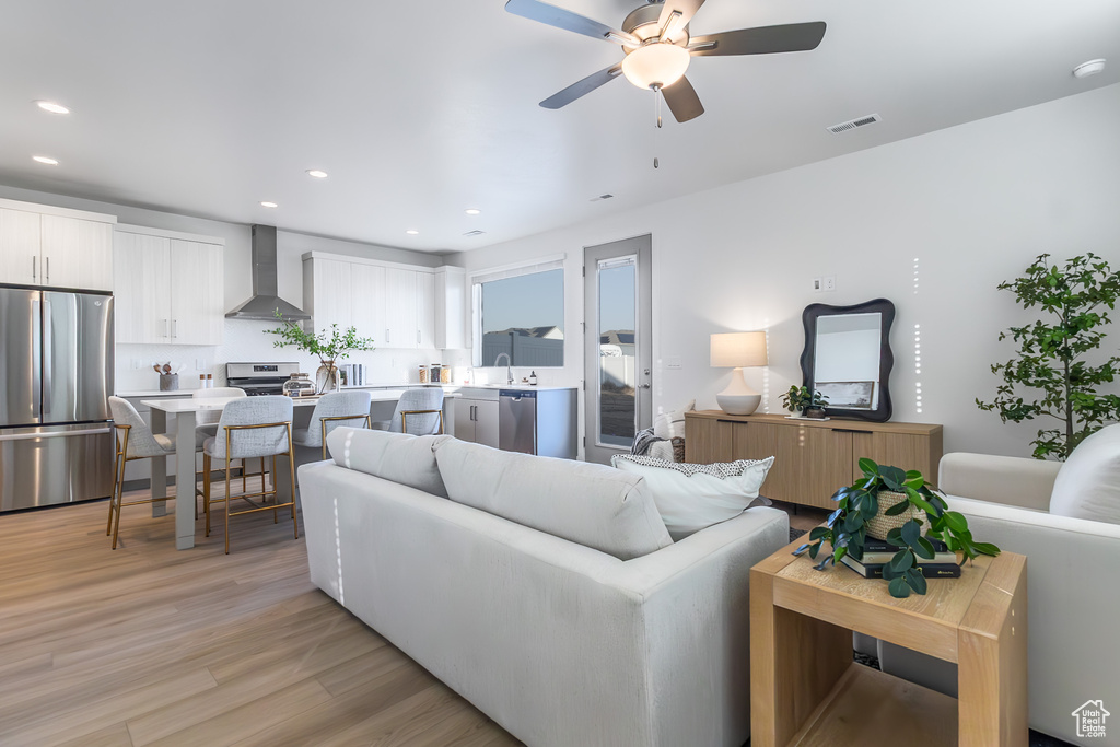 Living area featuring light wood-style flooring, ceiling fan, and recessed lighting