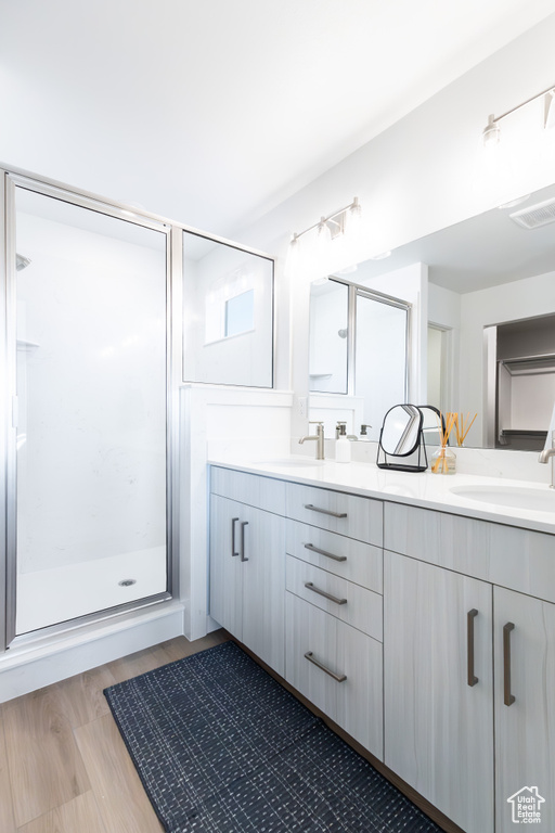 Full bathroom featuring double vanity, a shower stall, and wood finished floors