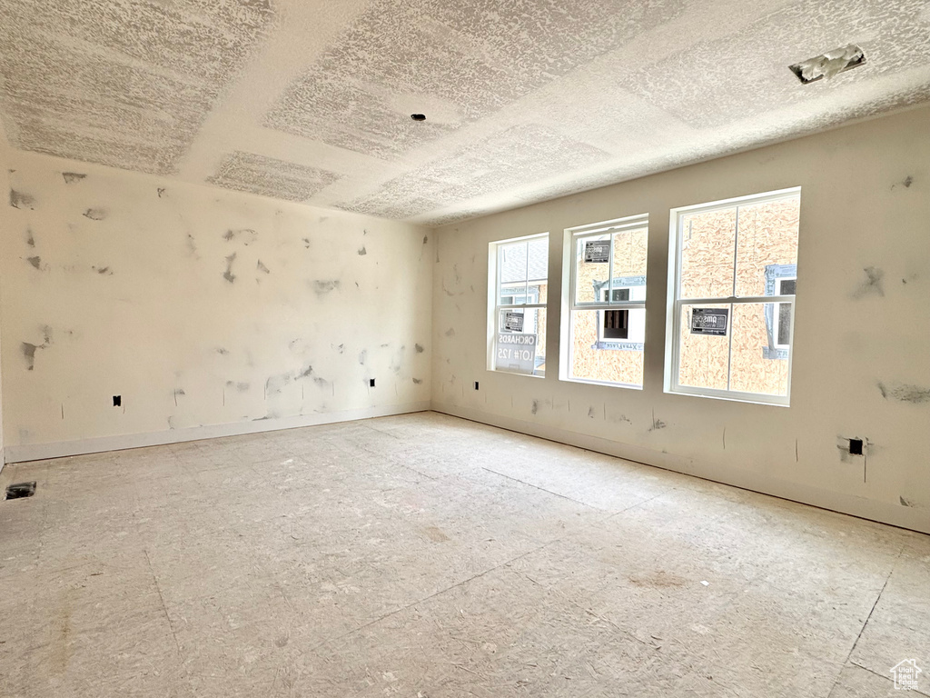 Empty room with a textured ceiling and baseboards