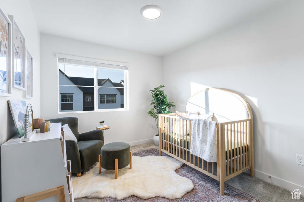 Carpeted bedroom featuring baseboards and a crib