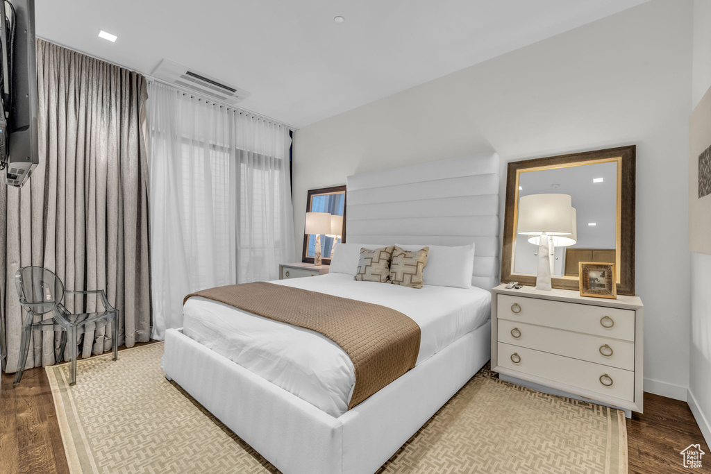 Bedroom with wood finished floors and a wall mounted air conditioner