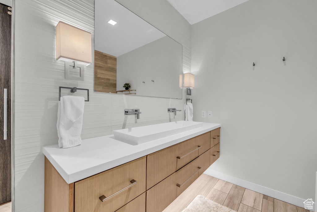Bathroom with backsplash, vanity, and wood finished floors