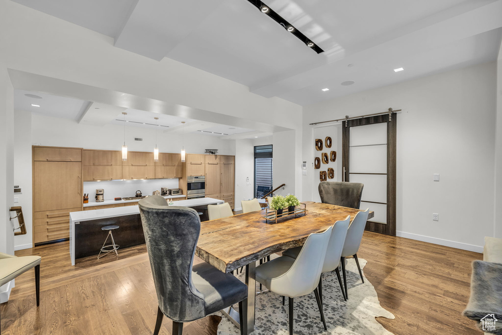 Dining room featuring light wood-style floors, a barn door, and recessed lighting